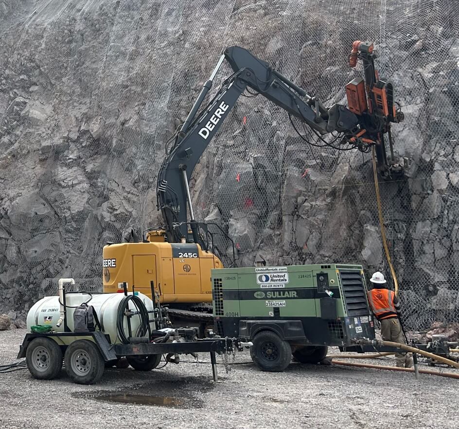 2021 Marini MR-A 300 mast attachment on a John Deere 245G excavator drilling a mesh-covered rock slope